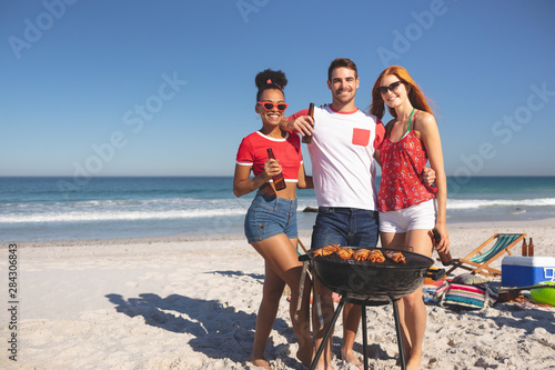 Group of friends holding beer bottles and looking at camera on the beach