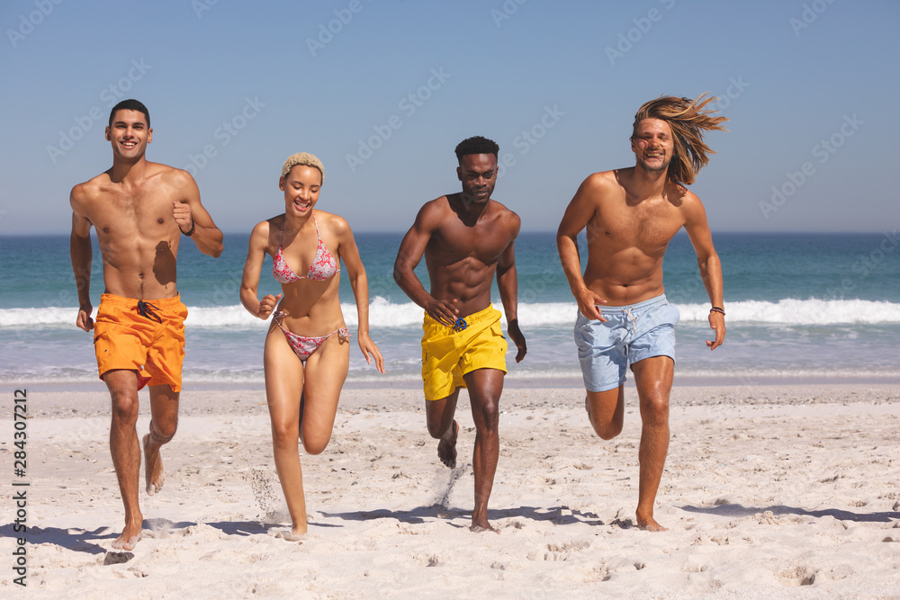 Group of friends running together on the beach