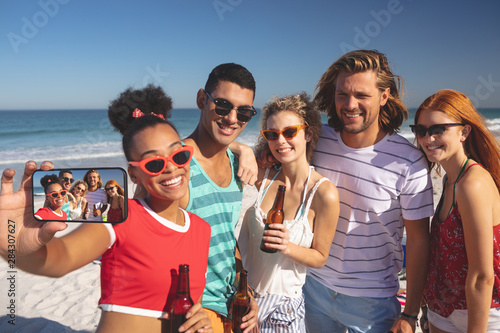 Group of friends taking selfie with mobile phone on the beach