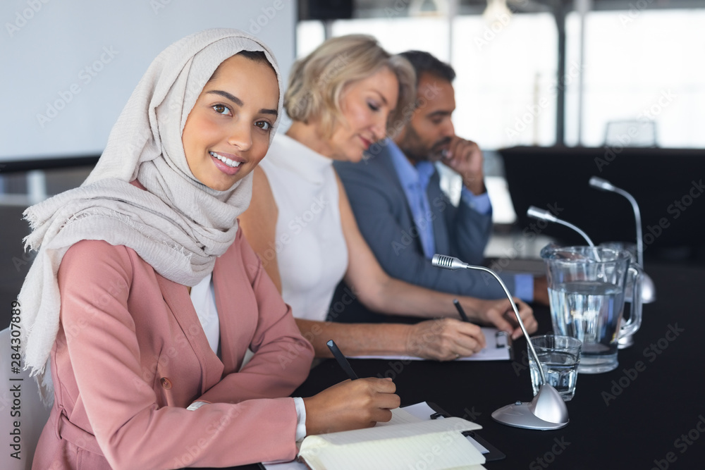 Fototapeta premium Businesswoman in hijab looking at camera at table in conference