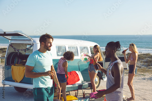 Group of friends having fun near camper van at beach © wavebreak3