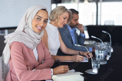 Businesswoman in hijab looking at camera at table in conference