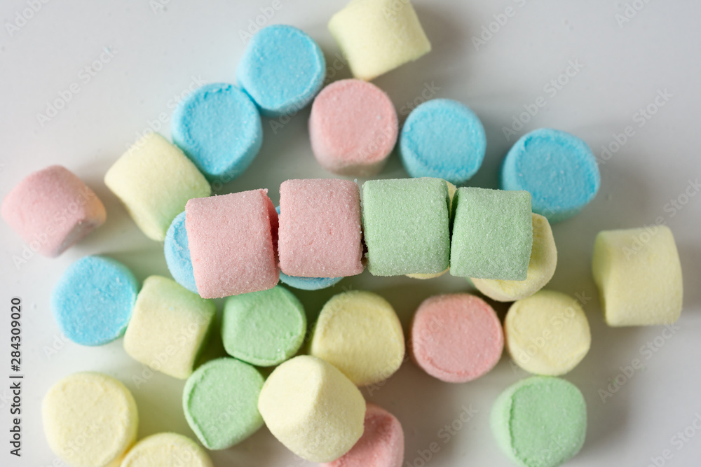 Colored marshmallows on a white background. A closeup of colored marshmallows. Colored marshmallows on a white background. A closeup of colored marshmallows.