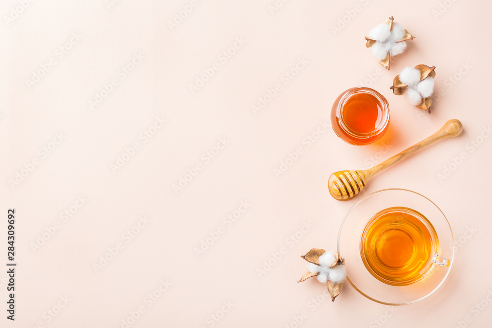 Cup of tea with honey on pastel pink, apricot background