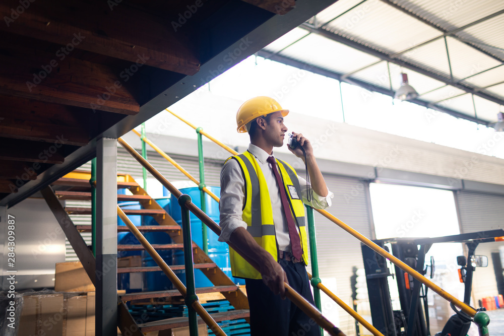 Male supervisor talking on walkie talkie on stairs