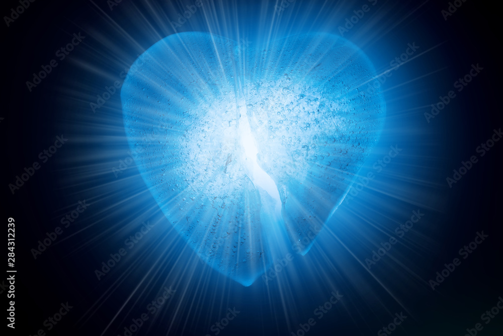 Ice frozen broken in half heart symbol of blue color close-up glowing in the dark in blue cold light. Texture of ice with bubbles. Symbol of a broken heart. Allegory of unhappy love. Ice frozen broken in half heart symbol of blue color close-up glowing in the dark in blue cold light. Texture of ice with bubbles. Symbol of a broken heart. Allegory of unhappy love.
