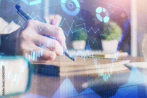 Financial forex charts displayed on woman's hand taking notes background. Concept of research. Double exposure