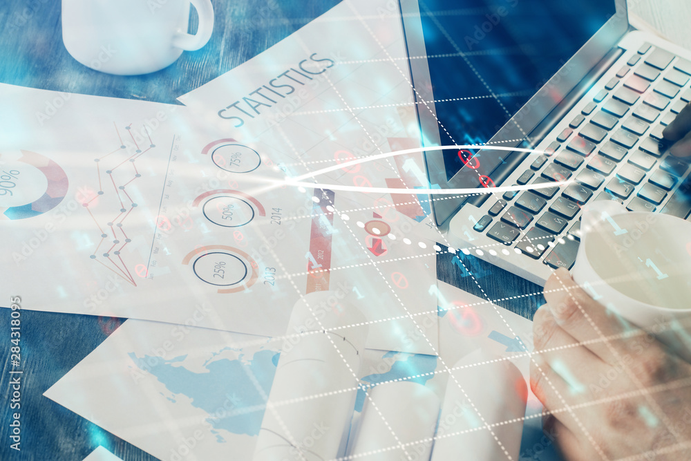 Double exposure of graph with man typing on computer in office on background. Concept of hard work. Double exposure of graph with man typing on computer in office on background. Concept of hard work.