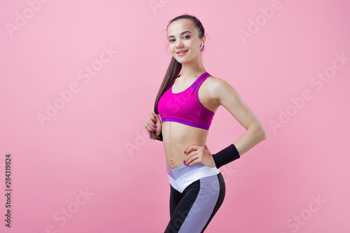Fototapeta Naklejka Na Ścianę i Meble -  Young athletic attractive girl brunette with a ponytail in a bright tight top straightens her hair, high ponytail.