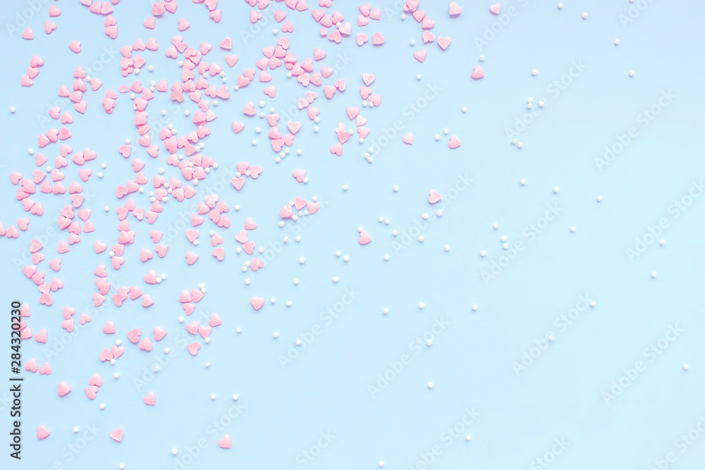 Festive romantic gentle abstract background for the design. Pink confetti in the shape of hearts on a blue background. Top view, flat lay composition. Copy space for text.	