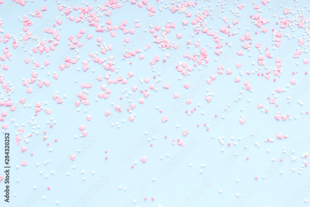 Festive romantic gentle abstract background for the design. Pink confetti in the shape of hearts on a blue background. Top view, flat lay composition. Copy space for text.	