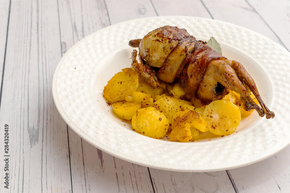 Roasted quail wrapped in bacon and sauteed potatoes Roasted quail wrapped in bacon and sauteed potatoes