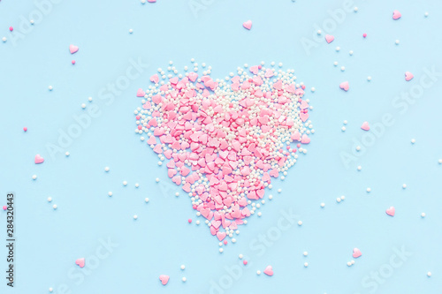 Valentine s Day. Heart made of pink confetti on blue background. Top view  flat lay composition. Copy space for text.