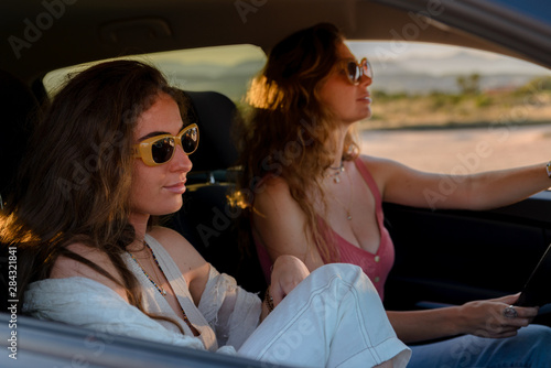 Two girls with sunglasses traveling by car on their vacation © MiguelZare