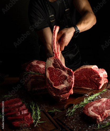 Butcher showing rack of ribs. Low key image, vertical orientation.