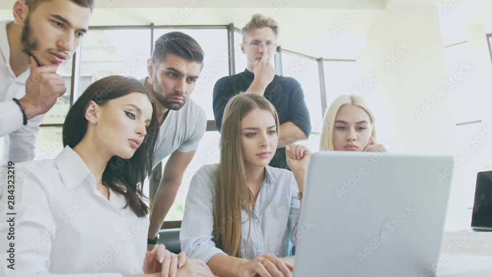Team of young people in work process in front of laptop Team of young people in work process in front of laptop