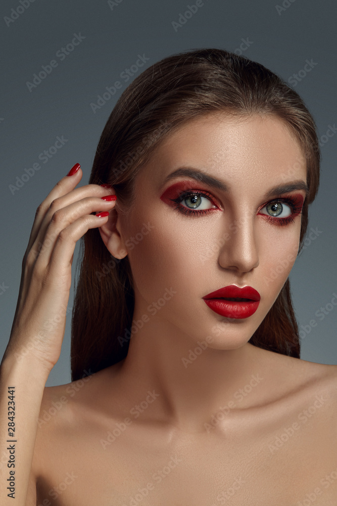 Close-up glamour portrait of a beautiful half-naked model with bright make-up posing over a gray background. Close-up glamour portrait of a beautiful half-naked model with bright make-up posing over a gray background.