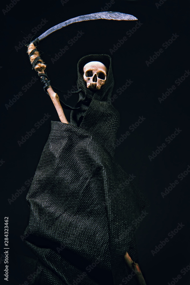 conventional death symbol with a slanting skull in a dark robe with a hood on a dark background conventional death symbol with a slanting skull in a dark robe with a hood on a dark background