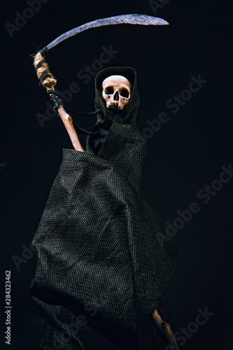 conventional death symbol with a slanting skull in a dark robe with a hood on a dark background