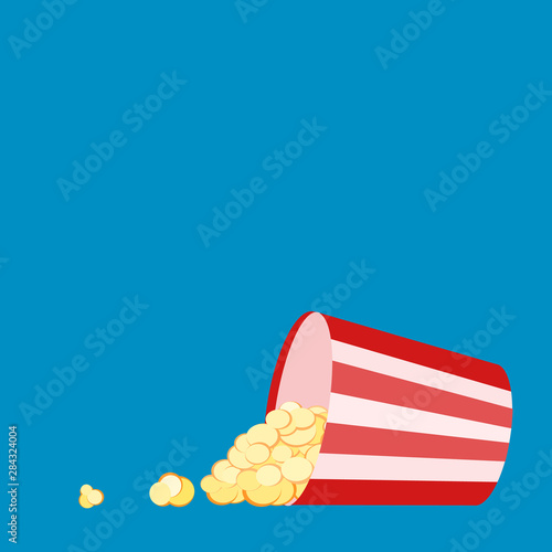 Red white striped container box lying tipped over with popcorn spread out. Pop corn bucket lying on its side with grains spilling out of it. Movie snack. Popcorn time. Watch and eat. Blue background