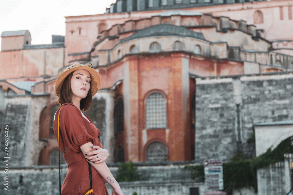 Beautiful girl with orange colored dress posing with Hagia Sophia during sunset from Istanbul