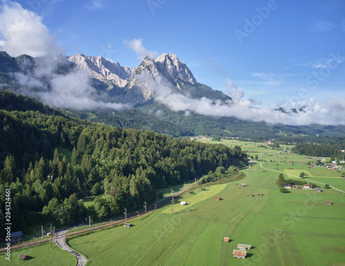 Aerial photo  of a meadow and pasture in Bavaria at the edge of the Alps with sheds and barns