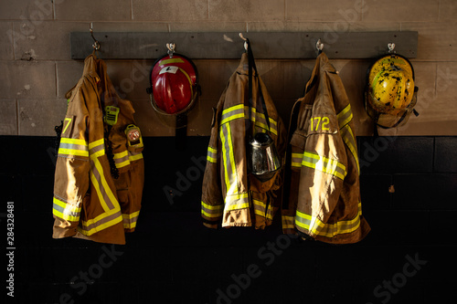 Dirty firefighter protection clothe and helmet hanging on the wall photo