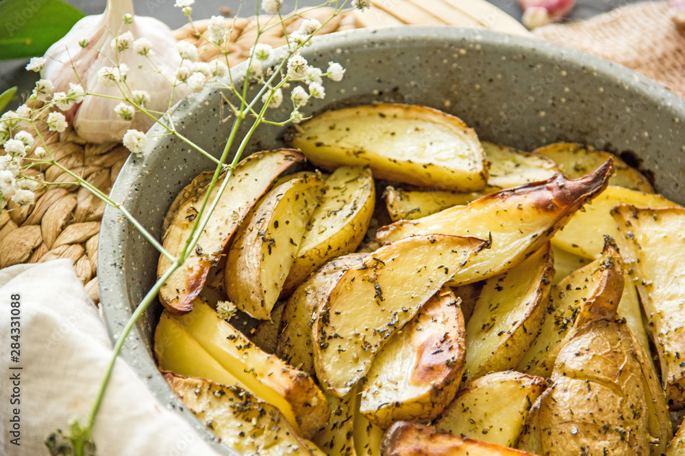 Oven baked potato in the oven with peel and spices in a baking dish. View from above. Potato wedges in peel, homemade lunch concept, dish with potatoes, baked potato recipe, Rustic potato Oven baked potato in the oven with peel and spices in a baking dish. View from above. Potato wedges in peel, homemade lunch concept, dish with potatoes, baked potato recipe, Rustic potato