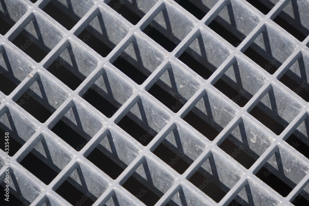 square geometry of the iron plates, sturdy bars. play of light and shadow, screensaver, background. diagonal lattice background from metal. Gray tint.