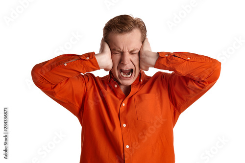 Close-up portrait of a ginger guy in orange shirt posing isolated on white background. Sincere emotions.