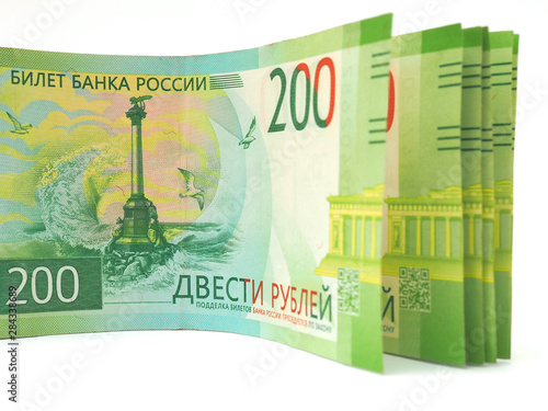 A pack of Russian bills of two hundred rubles is on a white surface. The banknote depicts a monument to the scuttled ships in Sevastopol. Close-up photo