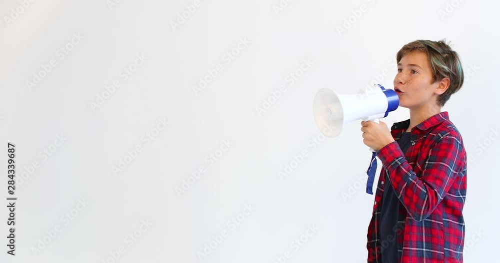 A cute teen screams into a megaphone. Communication and speech. A cute teen screams into a megaphone. Communication and speech.
