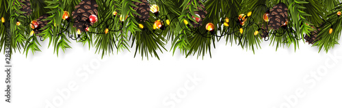Christmas border (Weihnachten Girlande) with fir branches, pine cones, holly, and string lights. Merry Christmas background with open space for your text. © detakstudio