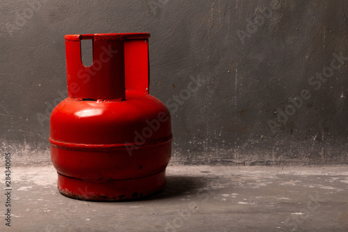 A red old gas cylinder stands on the floor near the wall.