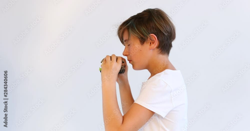 Cute boy goes and eats a Burger. Fast food. Teenagers. Cute boy goes and eats a Burger. Fast food. Teenagers.