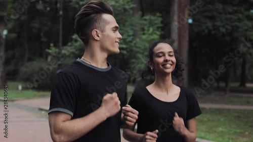 Couple Looking Excited Wearing a Jogging Suits Smiling and Chatting Running in the Park Concept Healthy Lifestyle Side view. photo