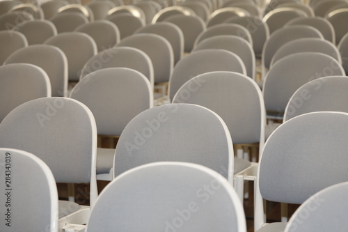 Sitzreihe mit vielen leeren, weißen Stühlen
