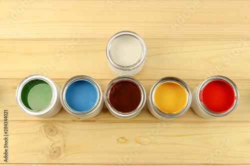 Flat composition of cans of paint, stand on a wooden background. Bright colours.