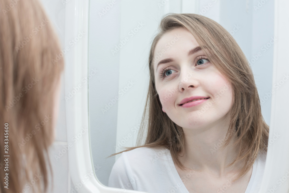 Reflection in the mirror of a smiling beautiful girl, looks in the mirror, close up Reflection in the mirror of a smiling beautiful girl, looks in the mirror, close up