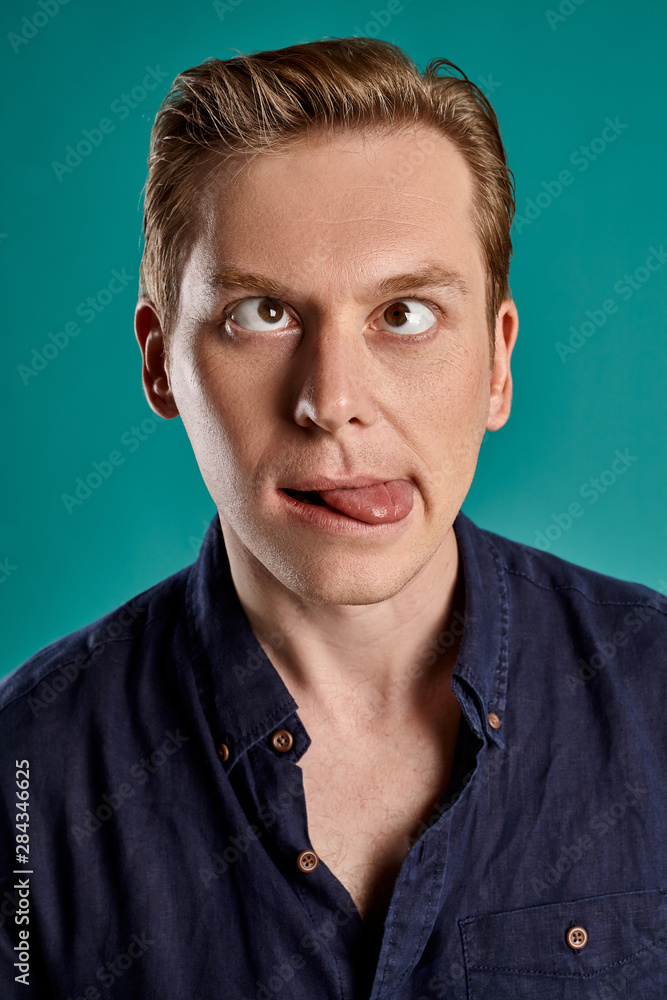 Close-up portrait of a ginger guy in navy t-shirt posing on blue background. Sincere emotions. Close-up portrait of a ginger guy in navy t-shirt posing on blue background. Sincere emotions.