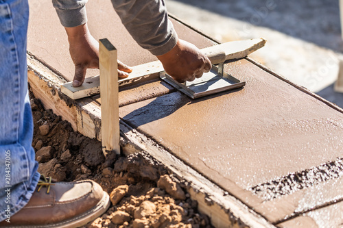 Construction Worker Using Hand Groover On Wet Cement Forming Coping Around New Pool photo