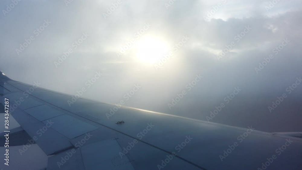 4K Aerial Point of view from airplane window of aircraft wing flying through above the clouds in a sunny day. 4K Aerial Point of view from airplane window of aircraft wing flying through above the clouds in a sunny day.