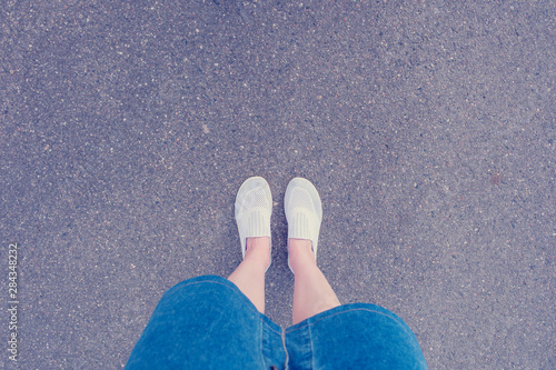Woman is about to take a step, asphalted street, feet in boots, close up, top view