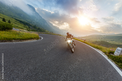Quadro su tela Motorcycle driver riding in Alpine landscape.