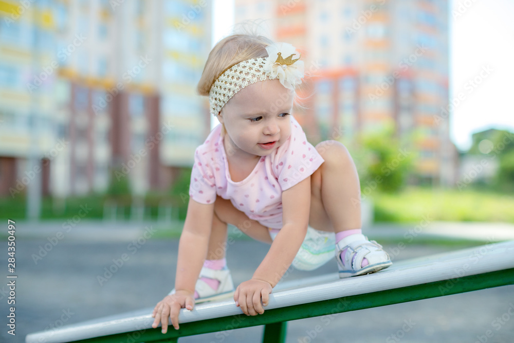 Happy kid enjoying active summer vacation. Adorable little child, blond cute toddler girl, having fun outdoors swinging on playground in the yard near house on a sunny day Happy kid enjoying active summer vacation. Adorable little child, blond cute toddler girl, having fun outdoors swinging on playground in the yard near house on a sunny day
