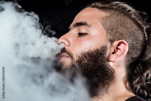 Close up face young man throw smoke through the nose with a long beard