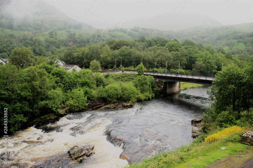The river Leven and bridge, in the village Kinlochleven, located on  the eastern end of Loch Leven.  It‘s raining. Glencoe National Nature Reserve, Highlands of Scotland, UK, Europe.