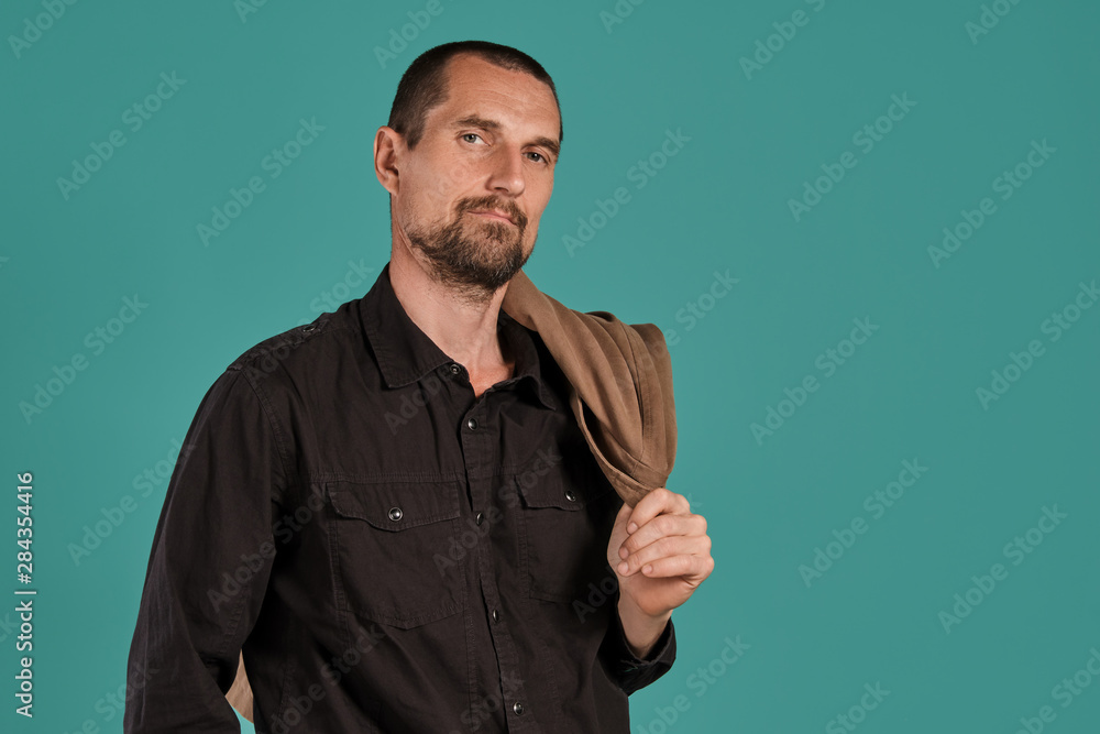 Middle-aged man with beard and mustache, wears black shirt, posing against a blue background. Sincere emotions concept. Middle-aged man with beard and mustache, wears black shirt, posing against a blue background. Sincere emotions concept.