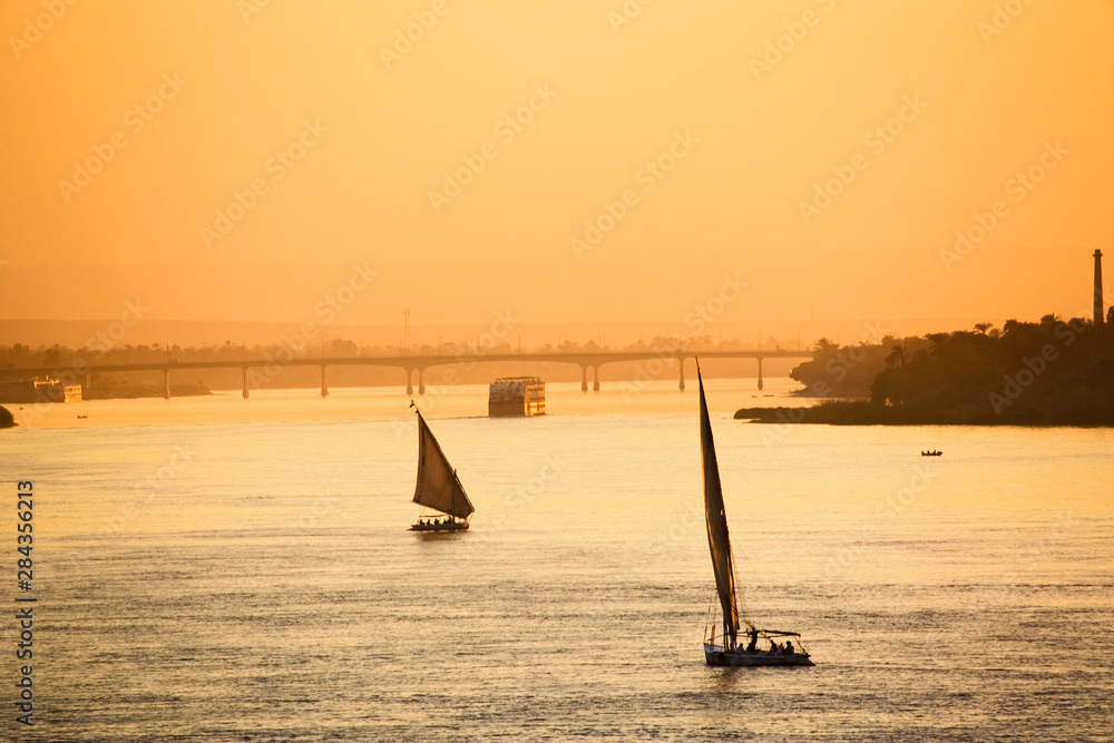 Pair of feluccas and sightseers on Nile River at sunset, modern day Luxor, or ancient Thebes