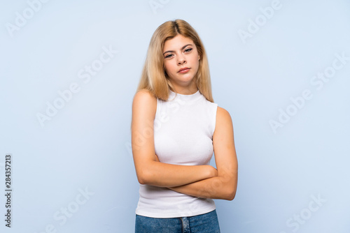 Teenager girl over isolated blue background keeps palm together. Person asks for something